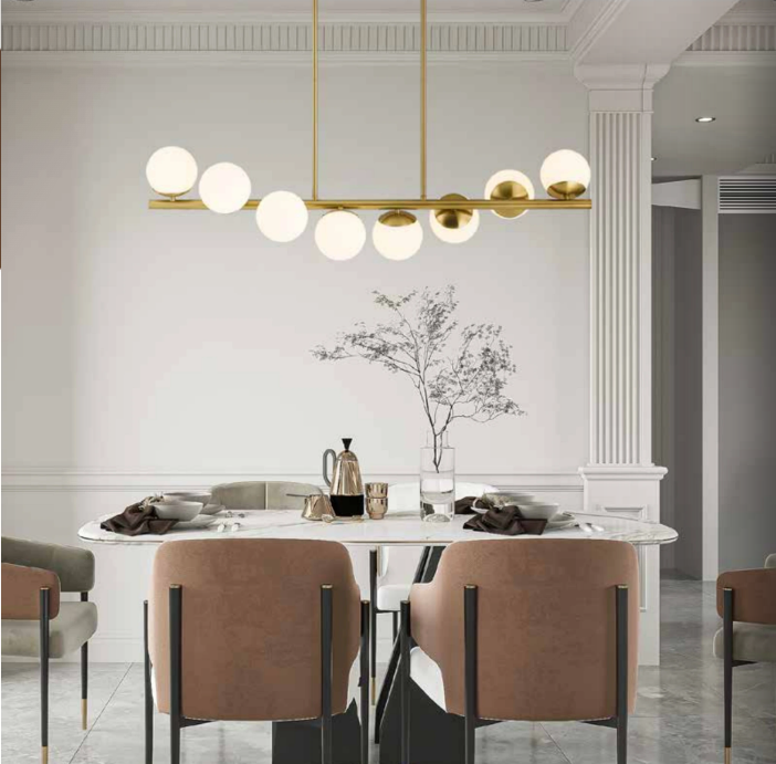 Linear gold chandelier spanning an oval marble dining table — proportional sizing for long tables