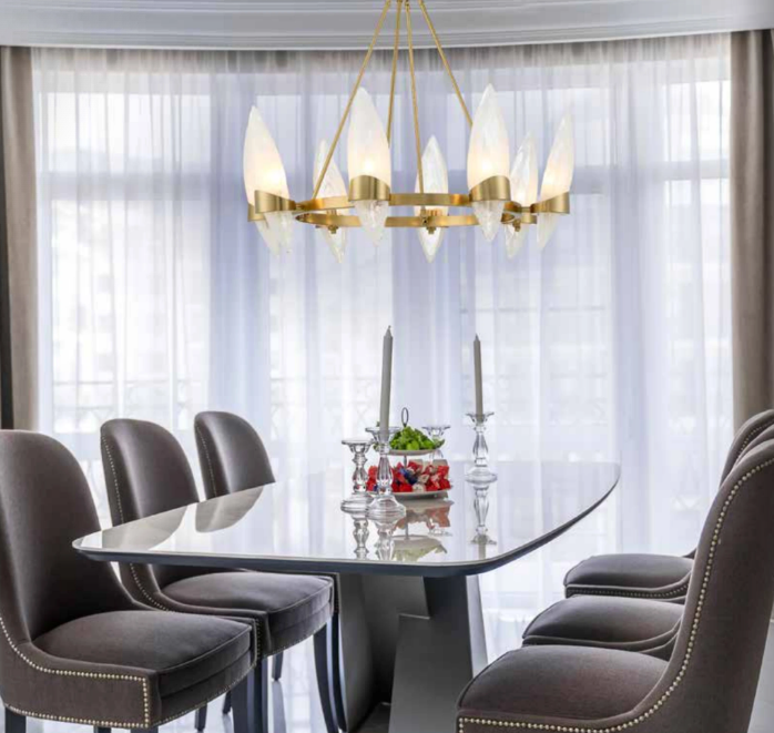 Round gold chandelier sized proportionally over a dining table in a finished dining room